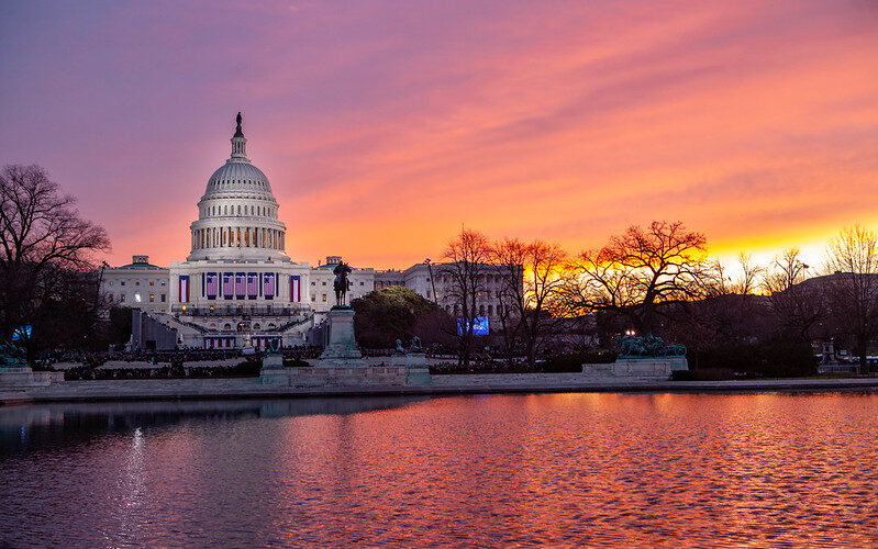 The sun is rising over the United States Capitol Building; this picture was taken in January 2013.